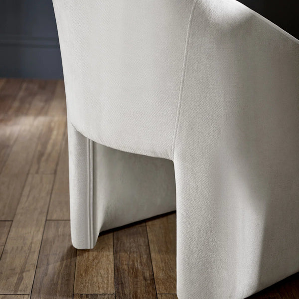 Close-up of a white upholstered chair on a wooden floor.