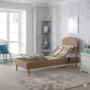 Beige adjustable bed in a room with a window, shelves, and decorative items.
