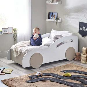 Child in a car-shaped bed with toys and a 'hello' sign in the room