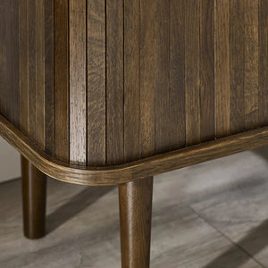 Close-up of a wooden side table with a striped pattern on a tiled floor.