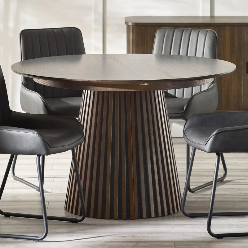Round dining table with a textured cylindrical base on a white background