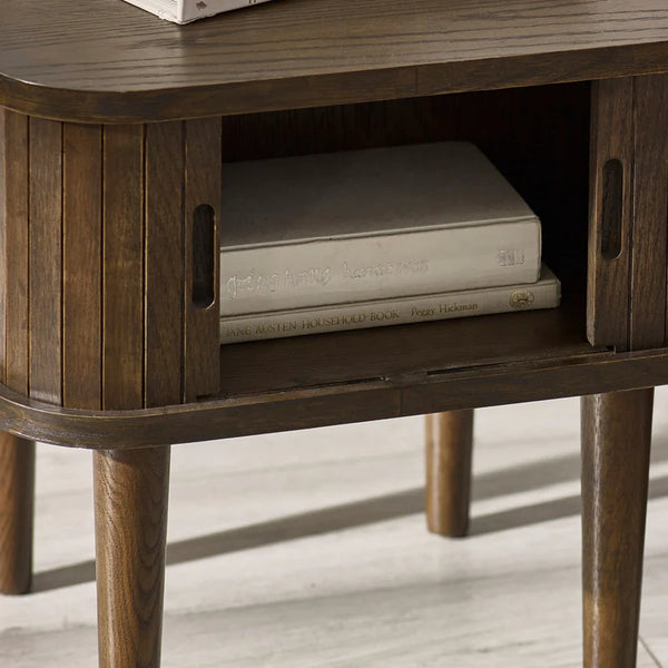 Wooden side table with a book inside its shelf