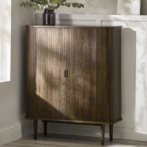 Wooden cabinet with a plant on top in a room with sunlight filtering through.