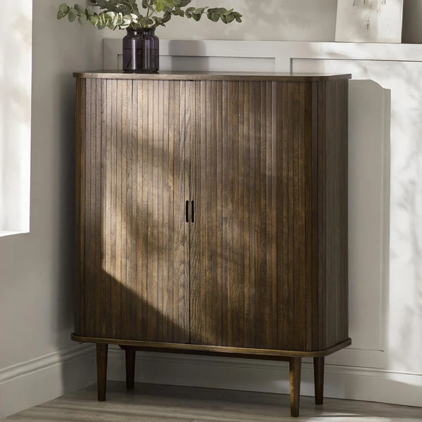 Wooden cabinet with a plant on top in a room with sunlight filtering through.