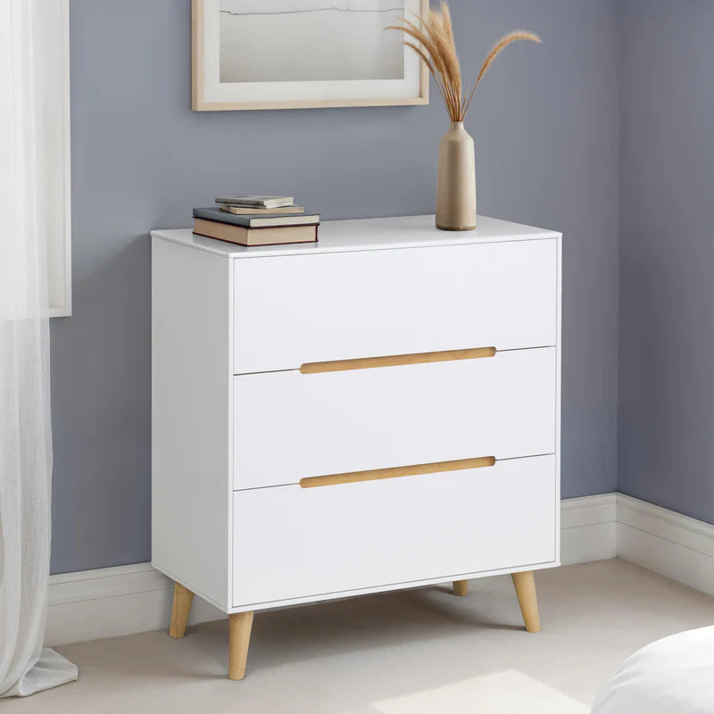 White dresser with three drawers and wooden handles on a white background