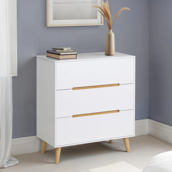 White dresser with gold handles against a gray wall