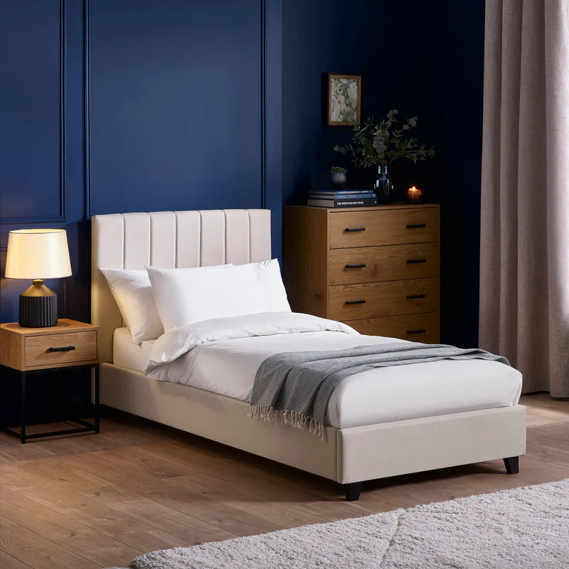 Beige upholstered bed with white bedding on a white background