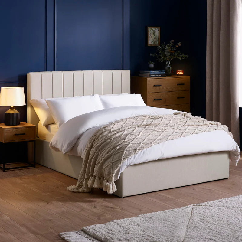 Beige upholstered bed with white bedding on a white background
