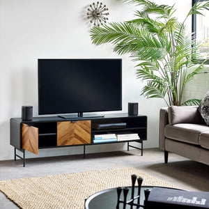 Modern living room with a TV on a wooden stand, sofa, and plants.