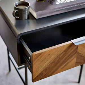 Wooden drawer being pulled out from a desk with a cup and book on top.