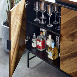 Wooden cabinet with open door revealing bottles and glasses on a shelf.
