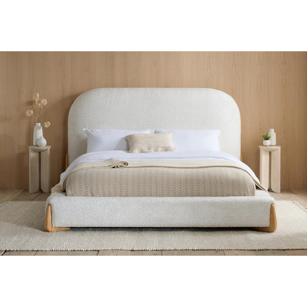 Beige upholstered bed with white bedding in a minimalistic bedroom setting.