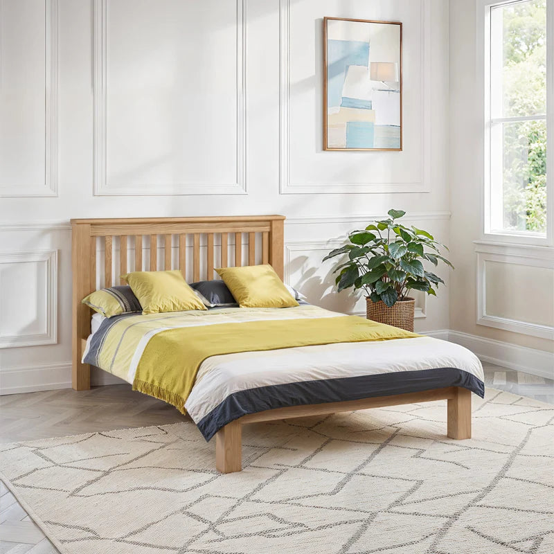 Wooden bed with green and white bedding on a white background