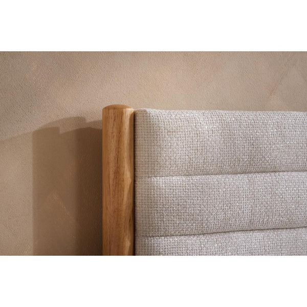 Close-up of a bed with wooden headboard and textured fabric headboard against a beige wall.