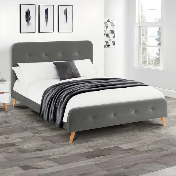 Gray upholstered bed with white bedding and a black blanket in a bedroom setting.