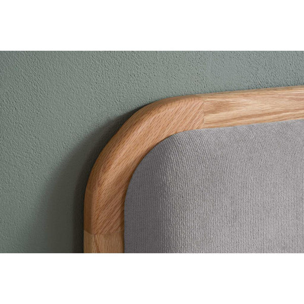 Gray upholstered chair with a wooden armrest against a green wall