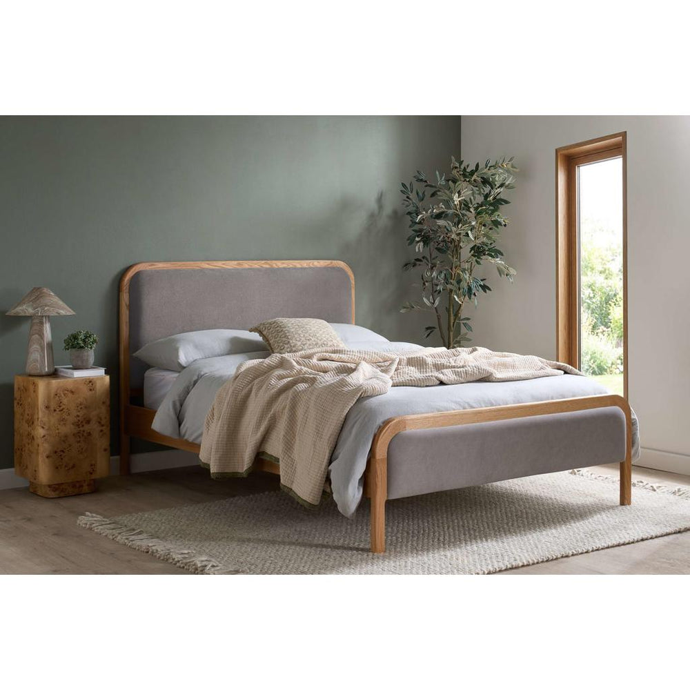 Wood and grey fabric bed frame with mattress on white background