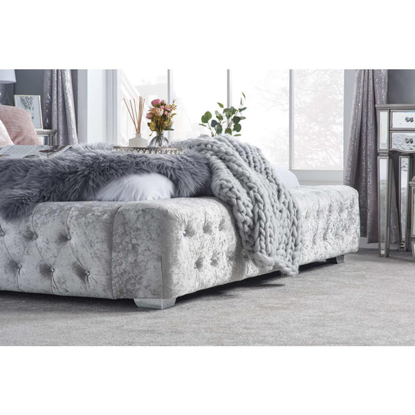 Gray tufted bed with a blanket in a bedroom setting