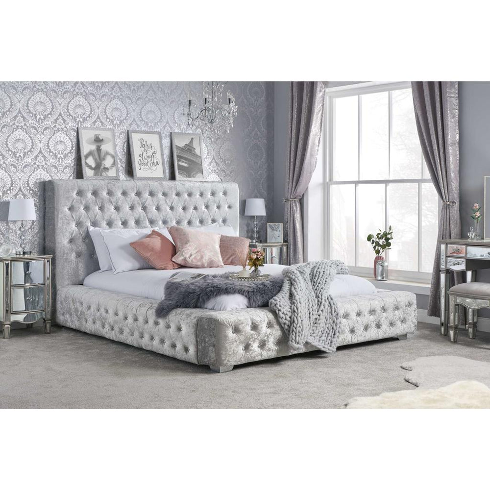 Gray tufted bed frame with mattress on a white background