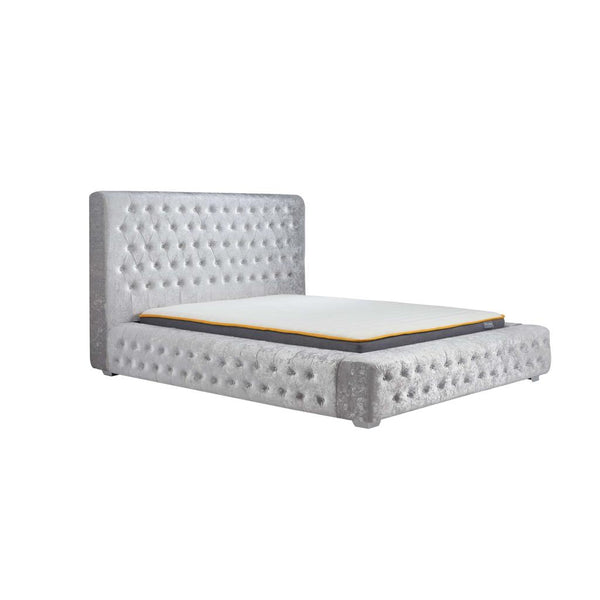 Gray tufted bed frame with mattress on a white background