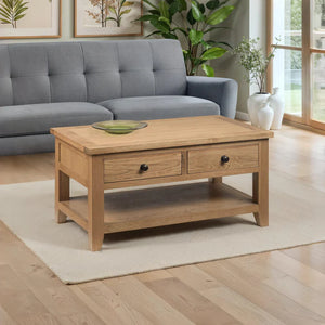 Wooden coffee table with two drawers in a living room setting with a grey sofa and plants.