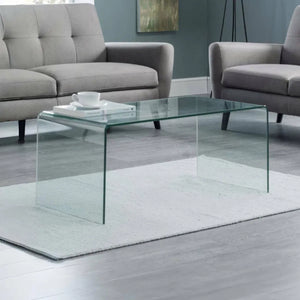Glass coffee table in a living room with gray sofa and rug