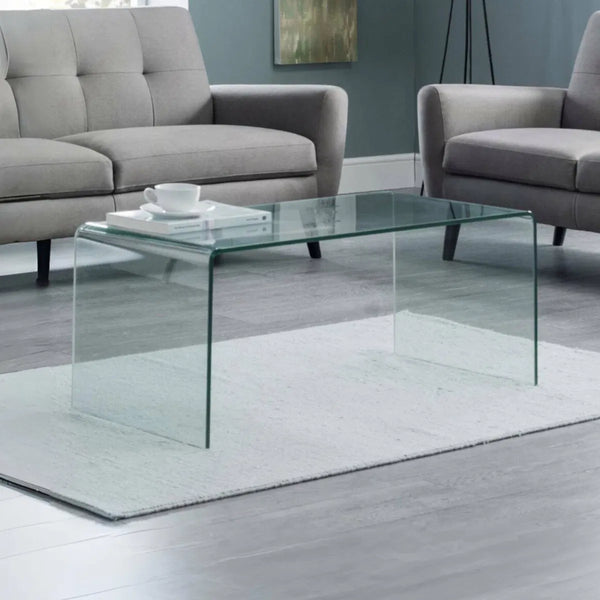 Glass coffee table in a living room with gray sofa and rug