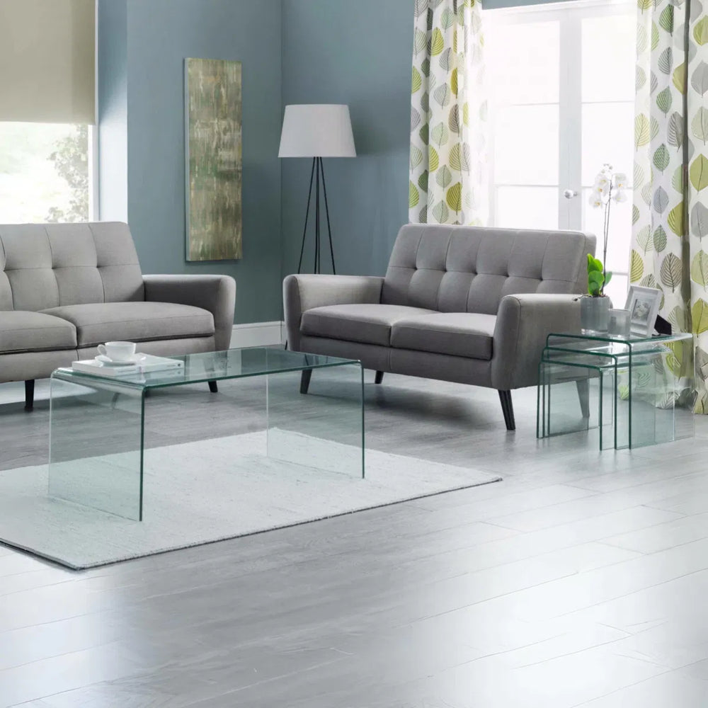 Set of clear glass nesting tables with a blue and green glass vase on top.