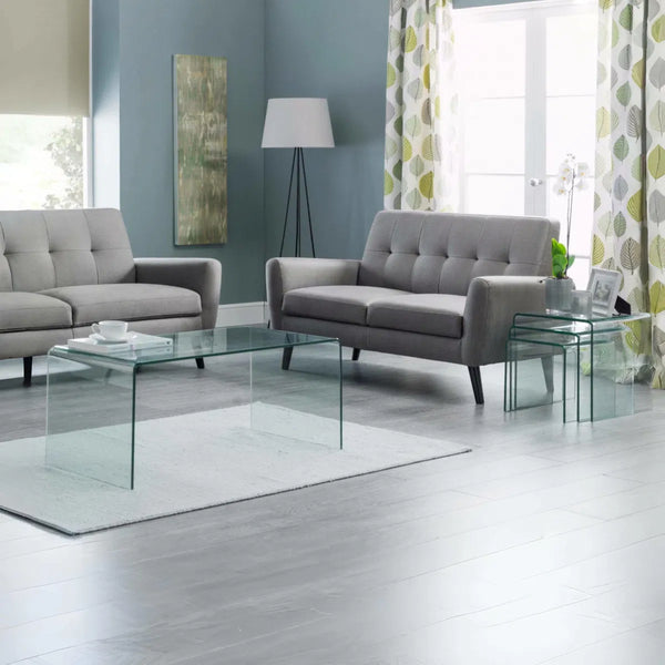 Modern living room with gray sofas, glass coffee table, and decorative elements.