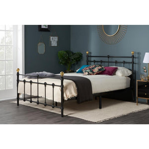 Black metal bed frame with decorative pillows in a bedroom setting.