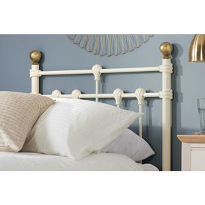 White metal headboard with gold accents on a bed against a blue wall.