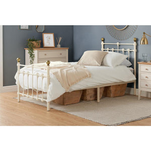 White metal bed with beige bedding in a bedroom setting.