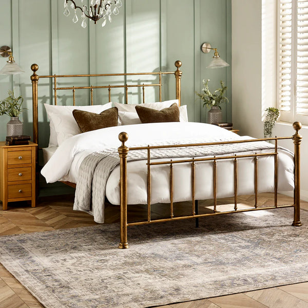 Gold metal bed frame with white bedding in a bedroom setting.
