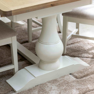 Wooden dining table with white pedestal base on a patterned rug