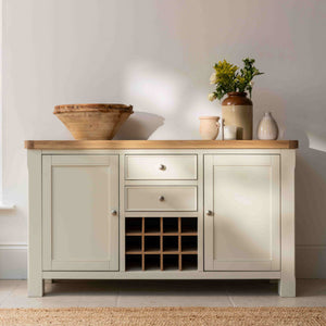 Light-colored wooden sideboard with a natural wood top, featuring decorative items, in a room with a window and rug.