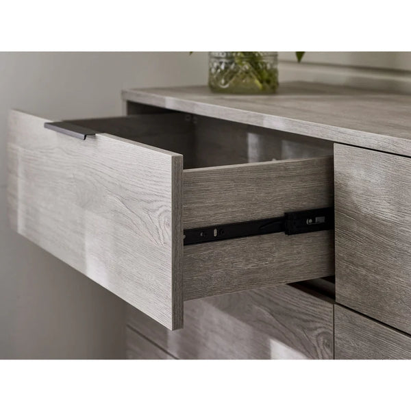 Wooden drawer with a metallic handle on a light-colored wooden surface.