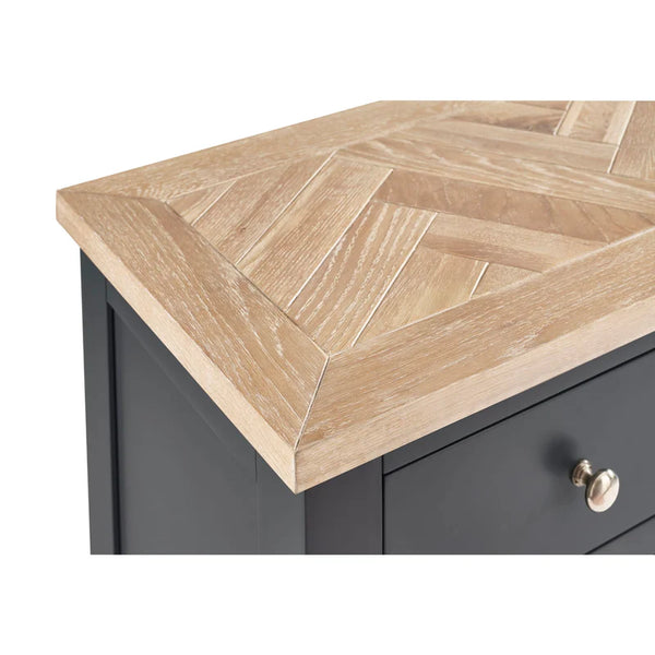 Wooden countertop with a geometric pattern on a gray cabinet.