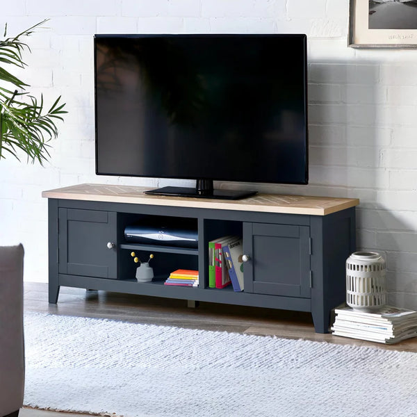 Grey TV stand with a wooden top displaying a television, books, and decorative items in a living room setting.