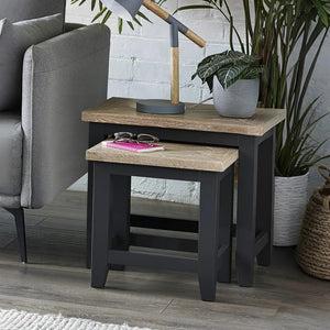 Side table with wooden top and black base in a living room setting