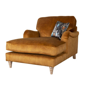 Brown velvet lounger chair with a patterned pillow on a white background