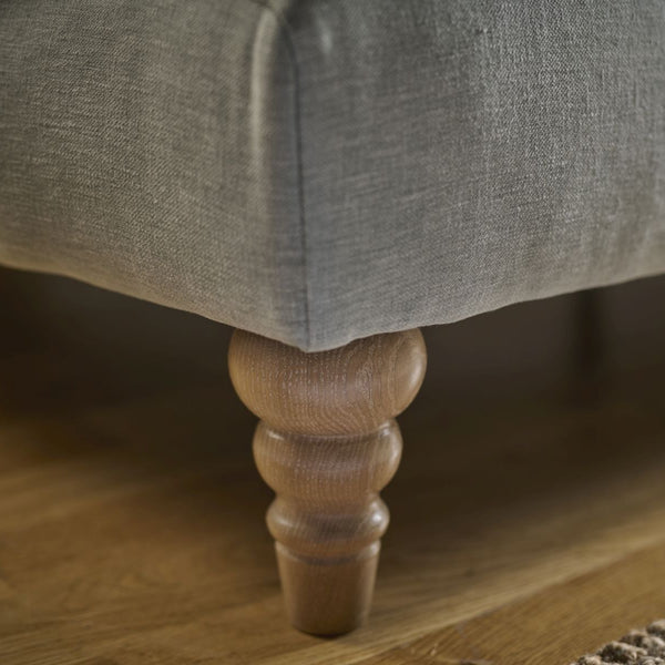 Gray upholstered chair with wooden leg on a wooden floor