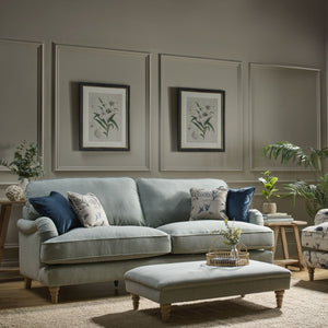 Living room with a gray sofa, armchair, and ottoman with decorative pillows.