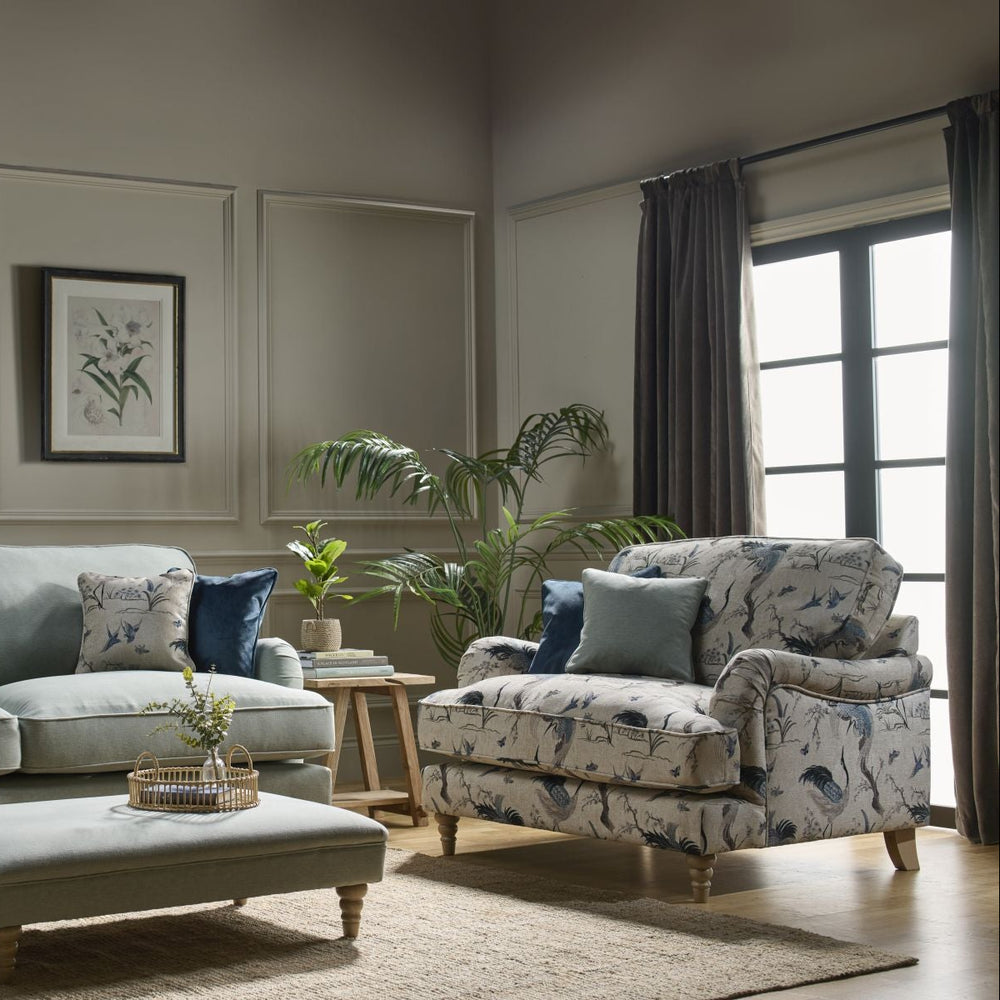 Brown velvet lounger chair with a patterned pillow on a white background