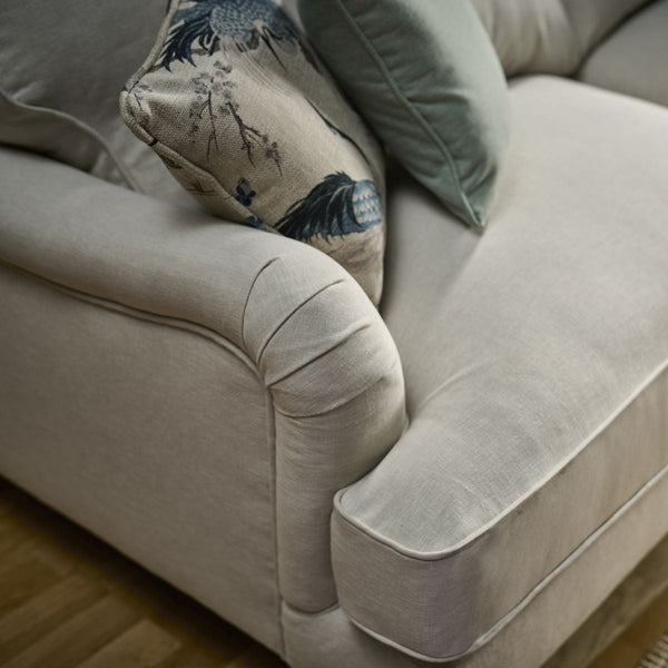 Beige sofa with a decorative pillow on a wooden floor