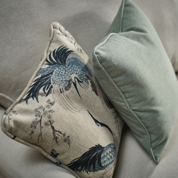 Decorative pillow with bird design on a gray sofa