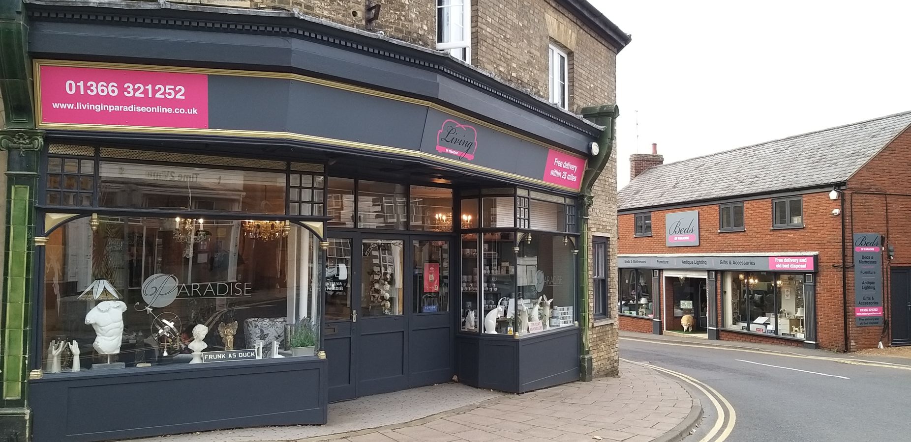 Shopfront with large windows displaying various items on a street corner.
