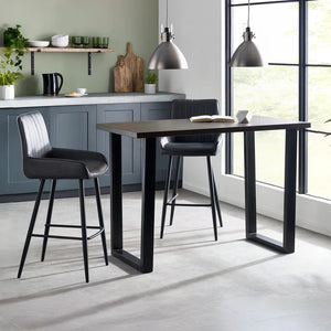 Modern kitchen with a black bar table and bar stools, featuring a green wall and large windows.