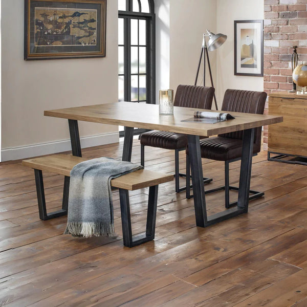 Dining area with wooden table, chairs, and bench on a wooden floor.
