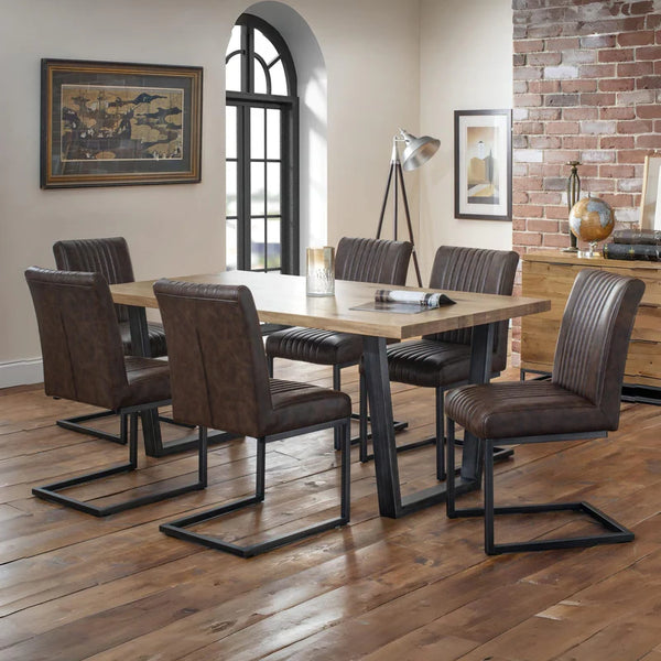 Dining room with wooden table and brown chairs against a brick wall.