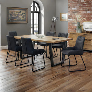 Dining room with wooden table and black chairs against a brick wall.